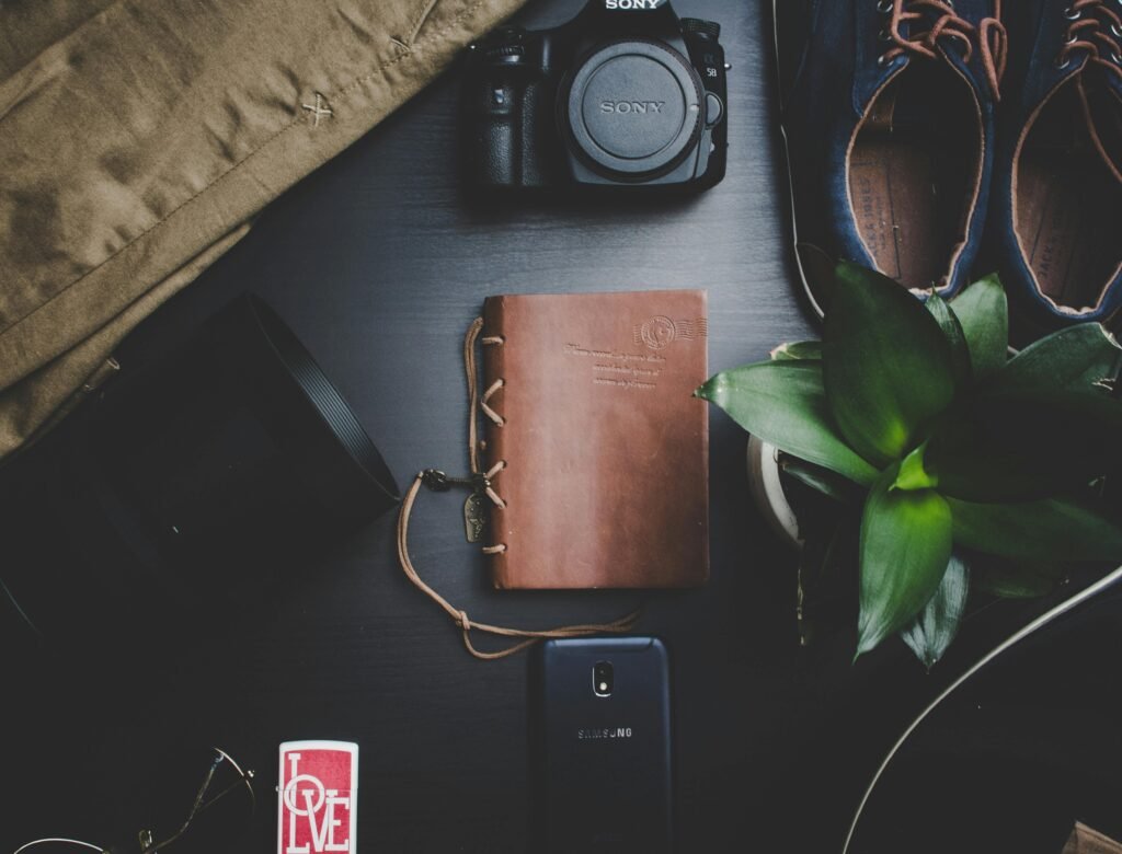 Black Sony Dslr Camera Beside Brown Notebook